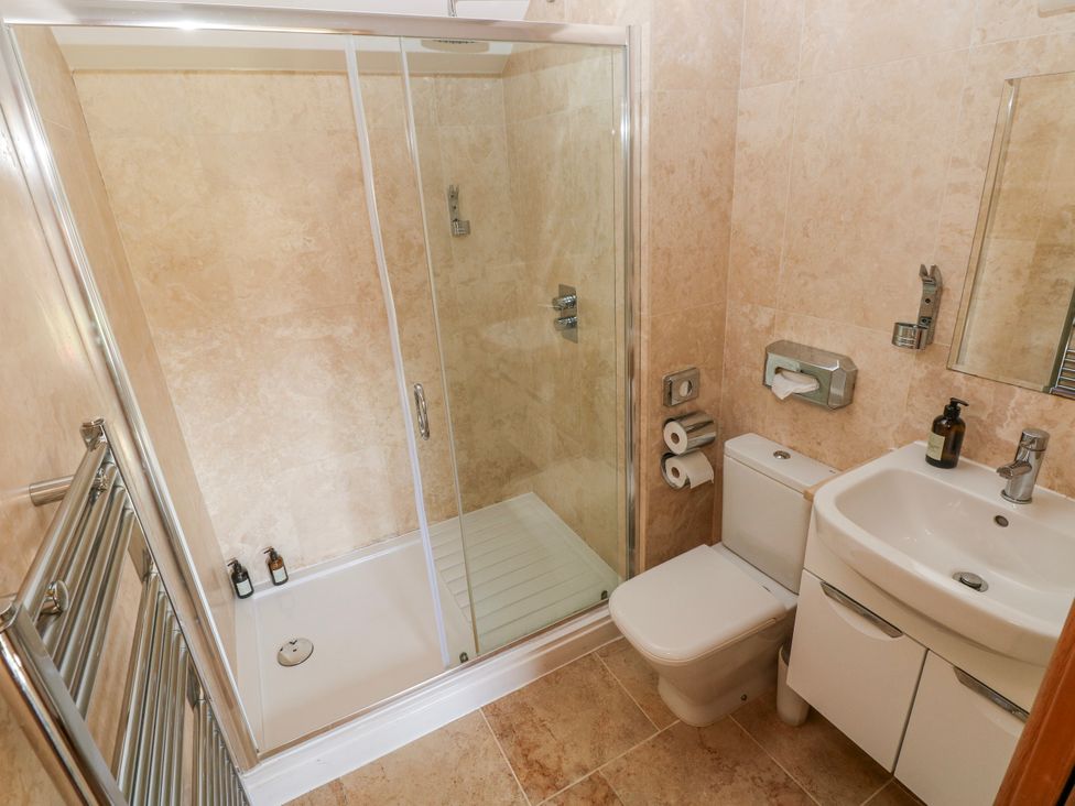 A bathroom with a shower, toilet, and sink at Willow Apartment Oldwalls, Llanrhidian, Gower