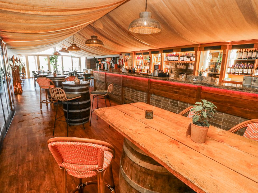An indoor dining area with wooden tables and a bar at Willow Apartment Oldwalls, Llanrhidian, Gower