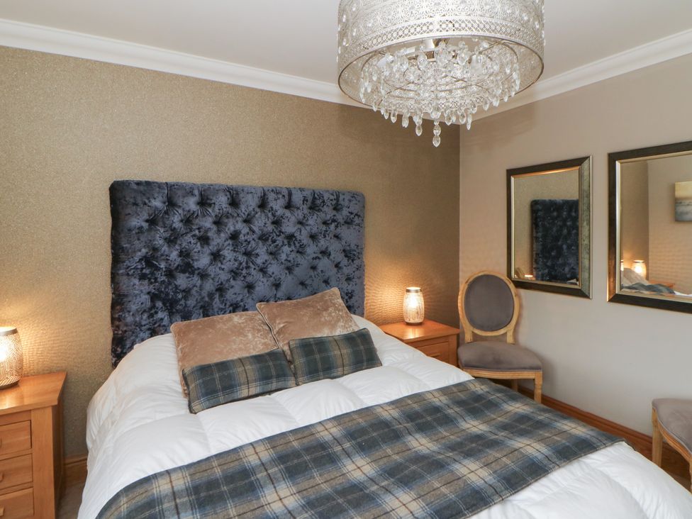 A bedroom with a bed, bedside tables, and a chair at Ivy Cottage in Swansea