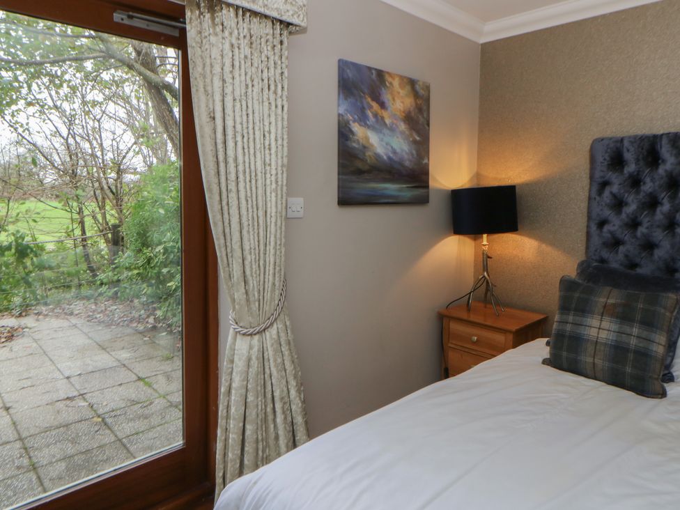 A bedroom with a bed and a bedside table at Ivy Cottage in Swansea