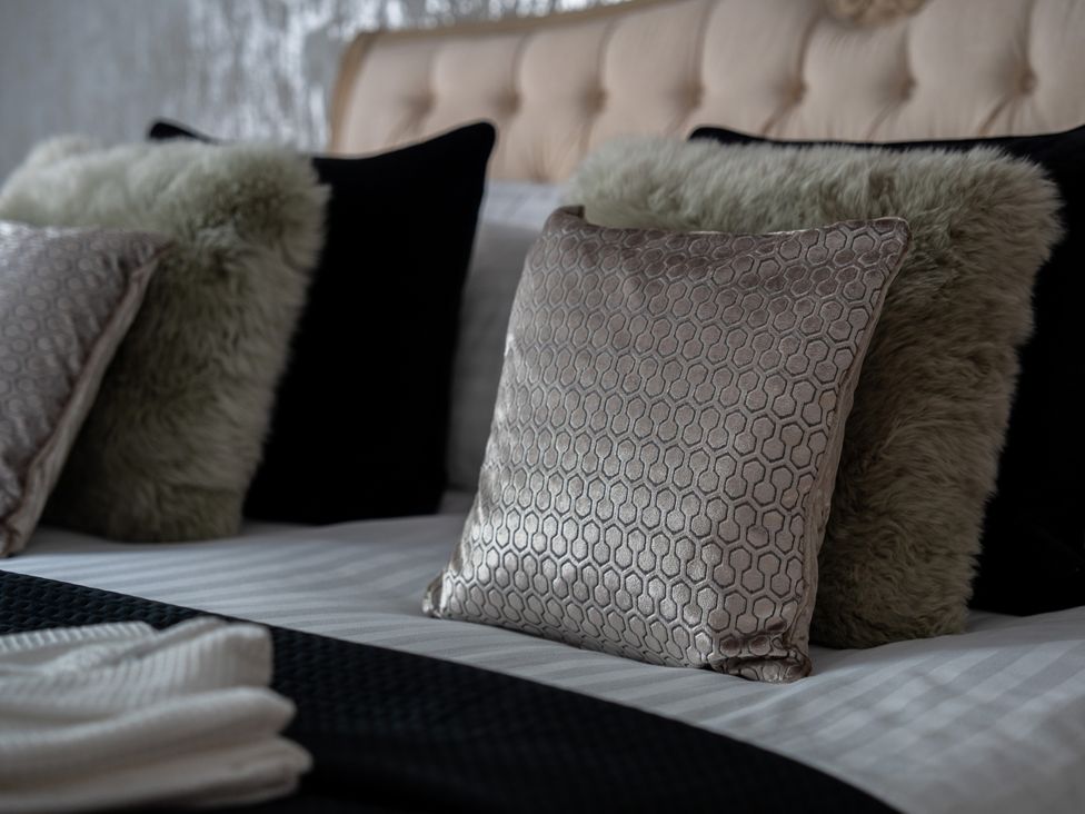 A bed with decorative pillows at Ivy Cottage in Oldwalls near Reynoldston