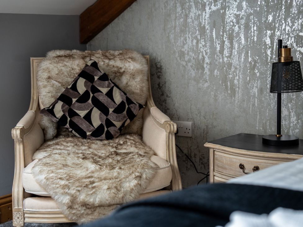 A living room with an armchair and cushion at Ivy Cottage Oldwalls near Reynoldston