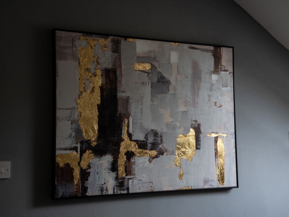 An abstract artwork with gold accents on a wall at Ivy Cottage Oldwalls near Reynoldston