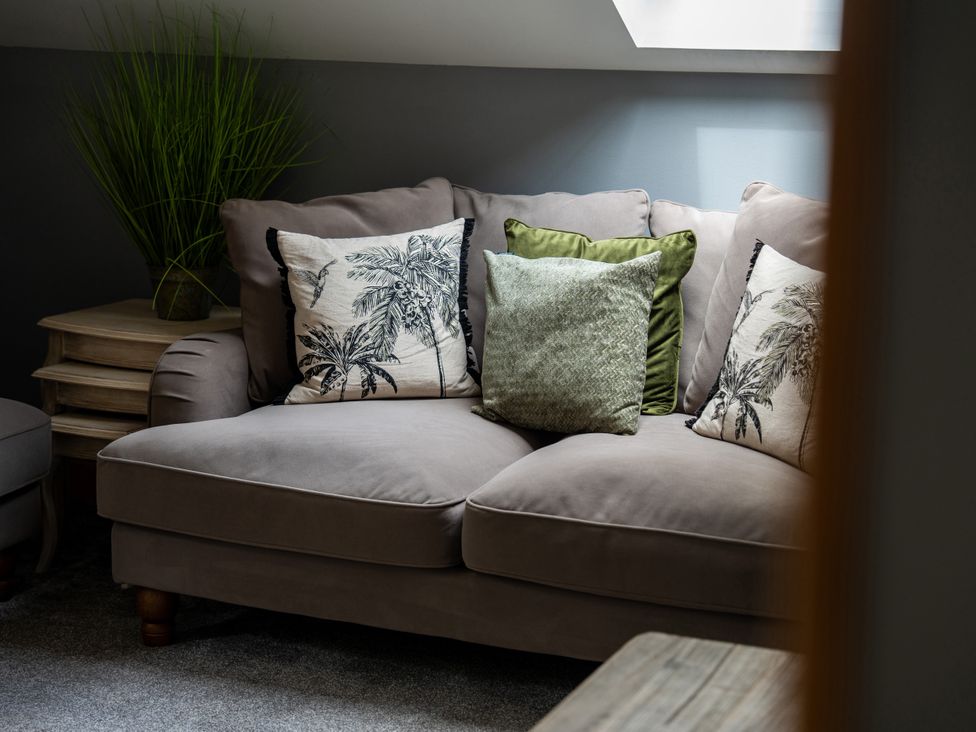 A sofa with cushions and a plant in a living room at Ivy Cottage Oldwalls near Reynoldston