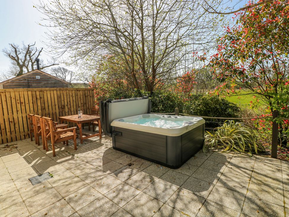 A garden with a hot tub and wooden furniture at Ivy Cottage Oldwalls, Llanrhidian, Gower