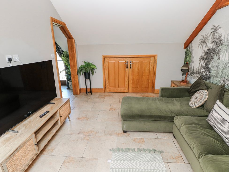 A living room with a sofa and television at Ivy Cottage in Oldwalls, Llanrhidian, Gower