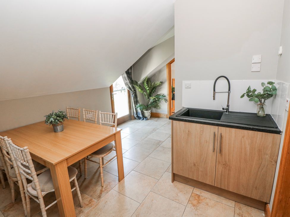 A kitchen with a dining table and a sink at Ivy Cottage in Oldwalls, Llanrhidian, Gower