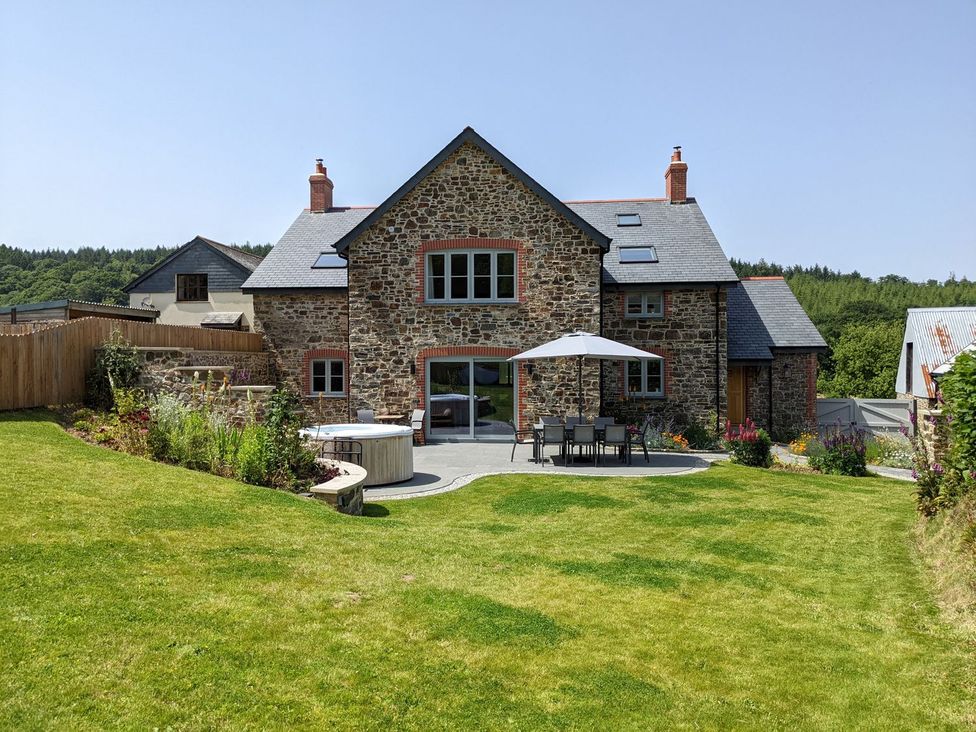 A house with patio furniture and a hot tub at Knowle House Okehampton