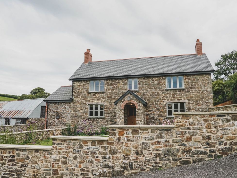 A house with a stone facade and a brick wall at Knowle House Okehampton