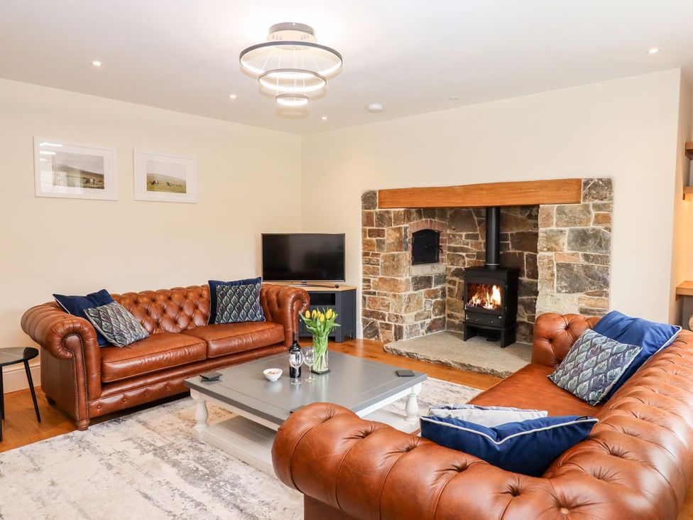 A living room with leather sofas and a fireplace at Knowle House in Okehampton