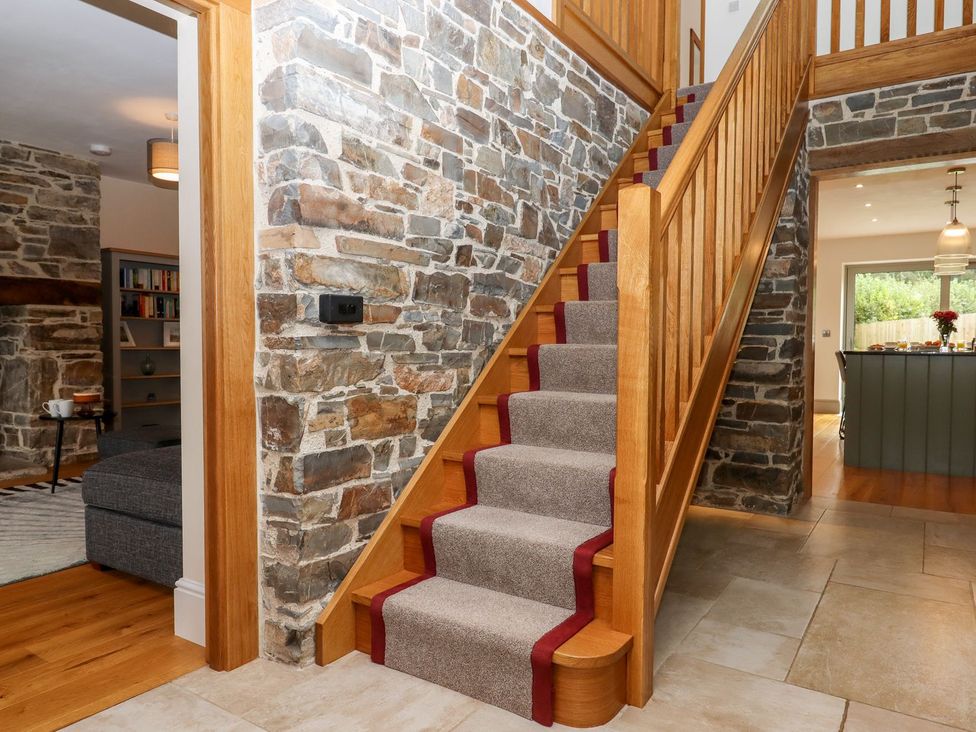 A staircase with a stone wall in a hallway at Knowle House in Okehampton