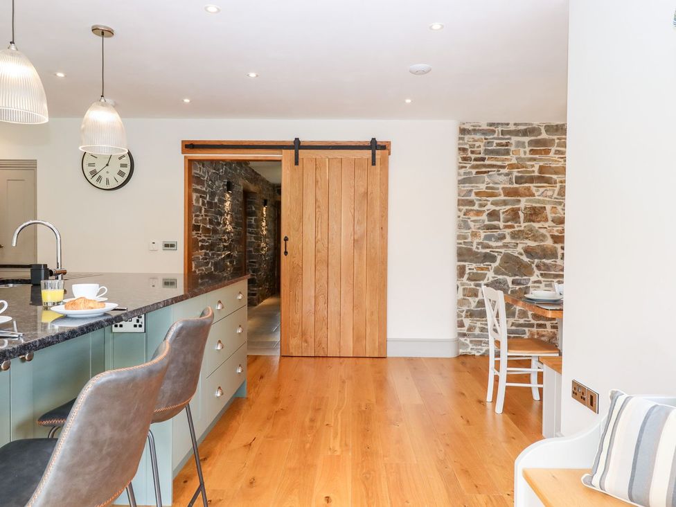 A kitchen with a wooden door and stone wall at Knowle House in Okehampton