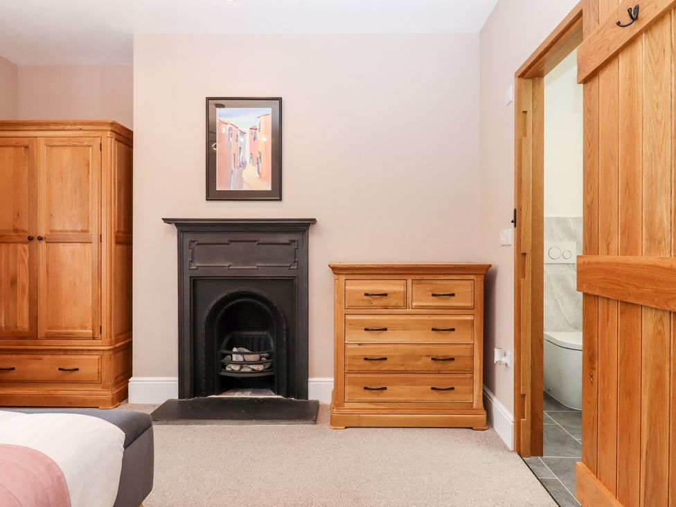 A bedroom with a wardrobe, chest of drawers, and a fireplace at Knowle House in Okehampton