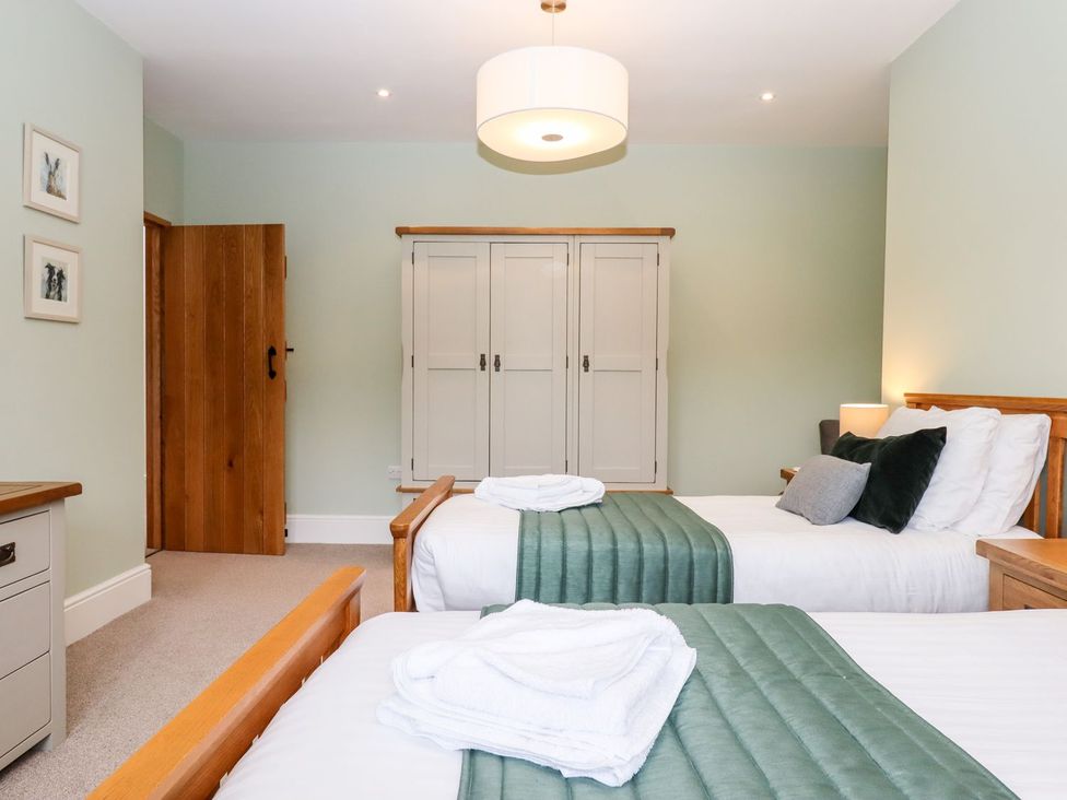 A bedroom with two beds and a wardrobe at Knowle House in Okehampton