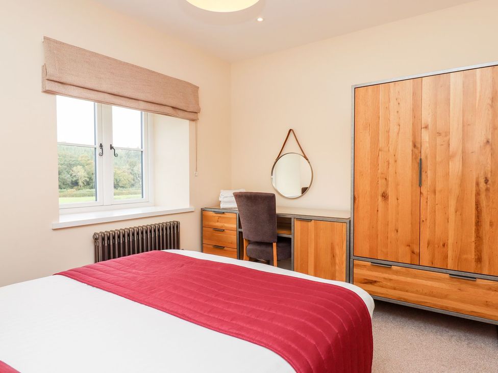 A bedroom with a bed, desk, and wardrobe at Knowle House in Okehampton