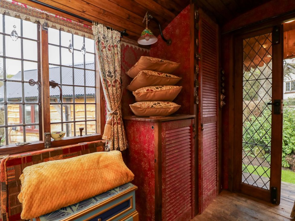 A room with a window, cushions, and a storage cabinet at The Gypsy Caravan in Marlborough