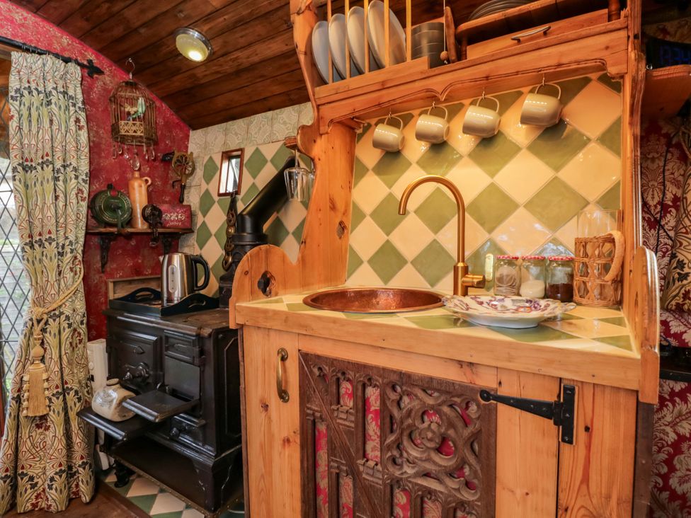 A kitchen with a sink, kettle, and wood stove at The Gypsy Caravan in Marlborough