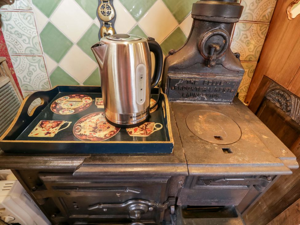 A kettle on a tray next to a wooden stove in the kitchen at The Gypsy Caravan in Marlborough