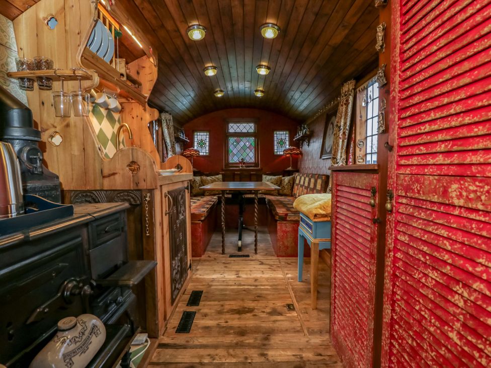 A living room with a stove, table, and couch at The Gypsy Caravan in Marlborough