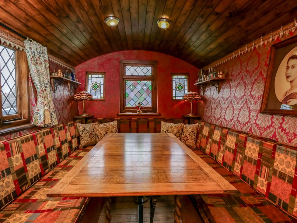 A dining room with a wooden table and bench seating at The Gypsy Caravan in Marlborough