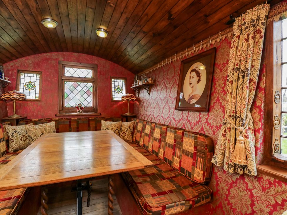 A dining room with a wooden table and benches at The Gypsy Caravan in Marlborough