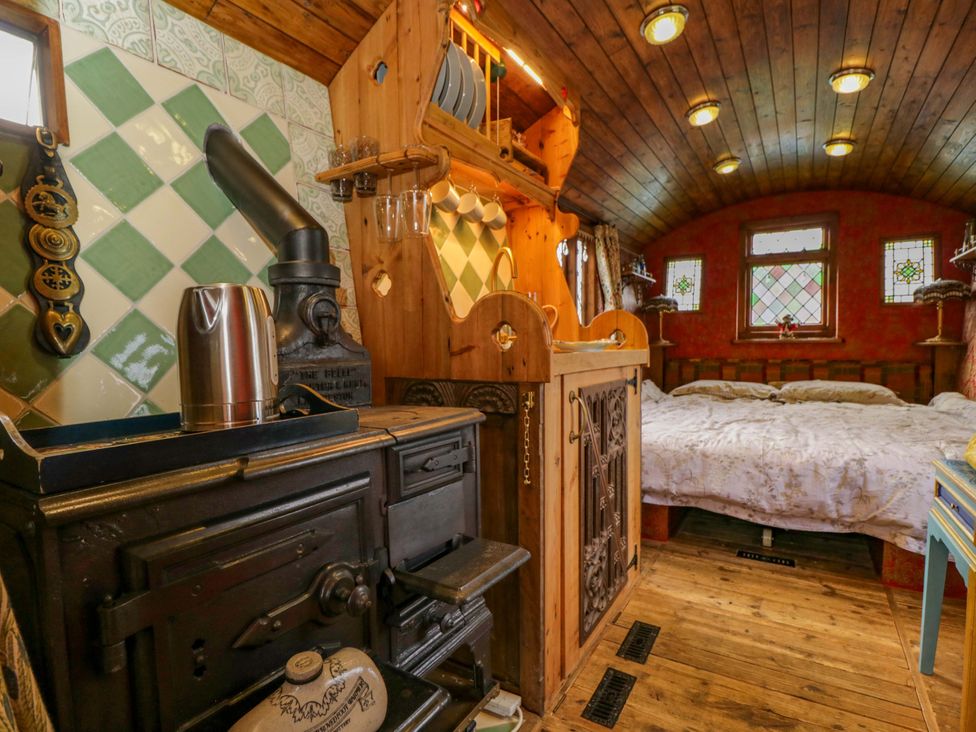 A bedroom with a wooden stove and a bed at The Gypsy Caravan in Marlborough