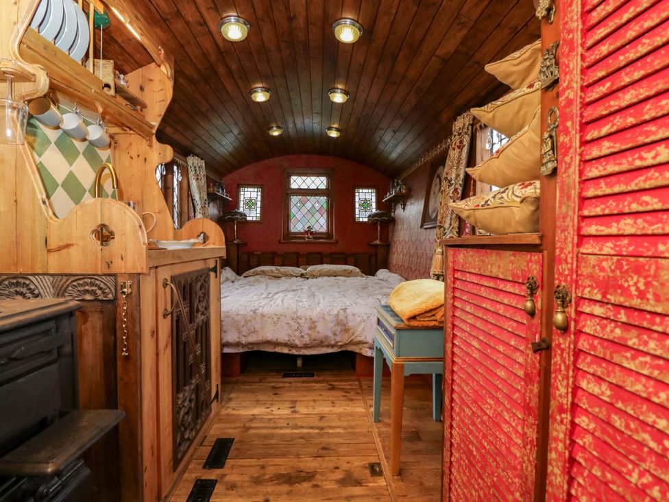 A bedroom with a bed and wooden furniture at The Gypsy Caravan in Marlborough