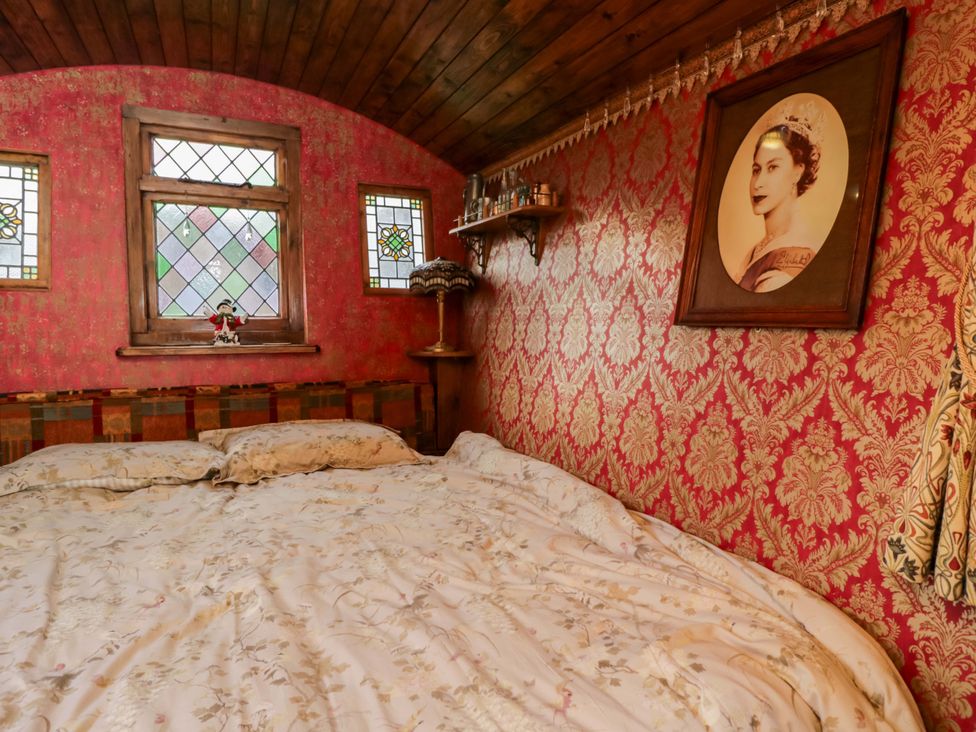 A bedroom with a bed and windows at The Gypsy Caravan in Marlborough