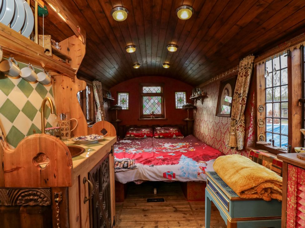 A bedroom with a bed and kitchen area at The Gypsy Caravan in Marlborough