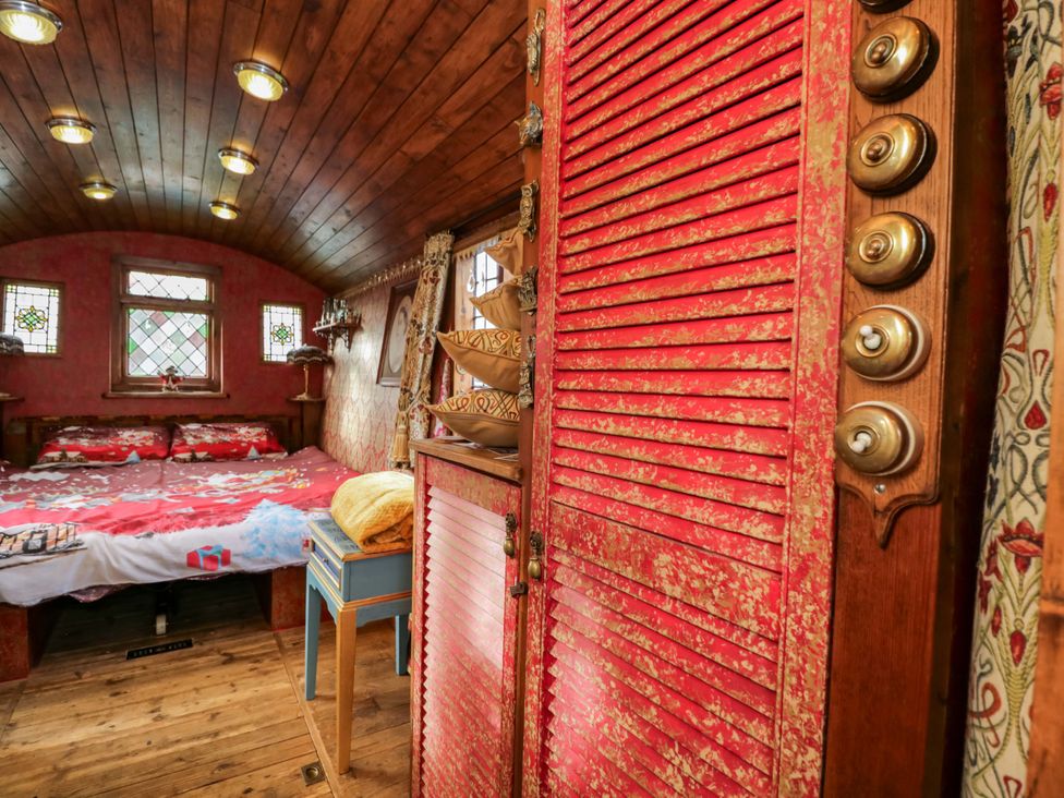 A bedroom with a bed, window, shelves, and wardrobe at The Gypsy Caravan in Marlborough