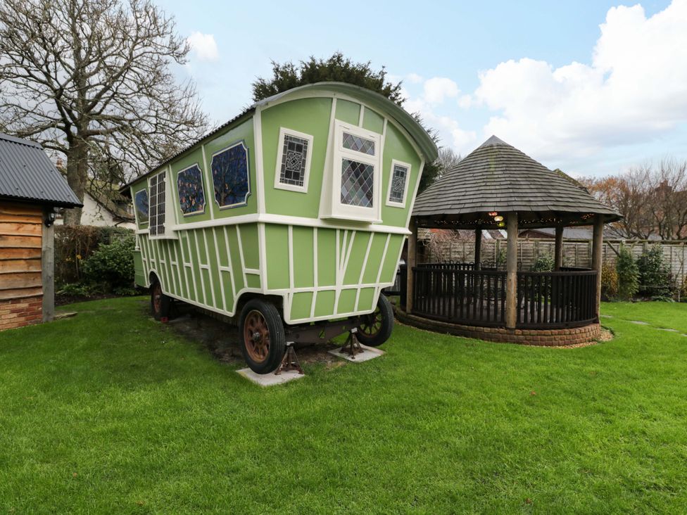 A green caravan and a gazebo in a garden at The Gypsy Caravan in Marlborough