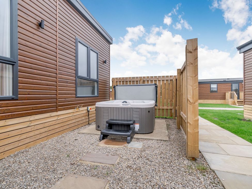 An outdoor area with a hot tub and wooden fence at Pear Tree Spa Carlton Miniott near Thirsk