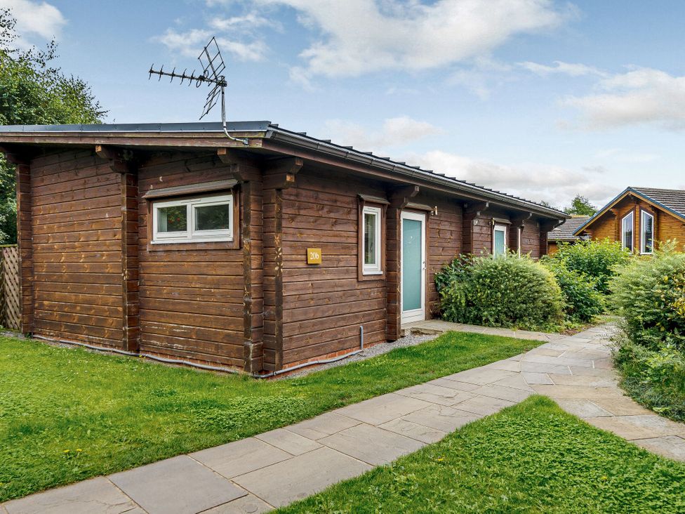 A wooden cabin with a pathway and bushes at Chestnut Spa (Pet) Carlton Miniott near Thirsk
