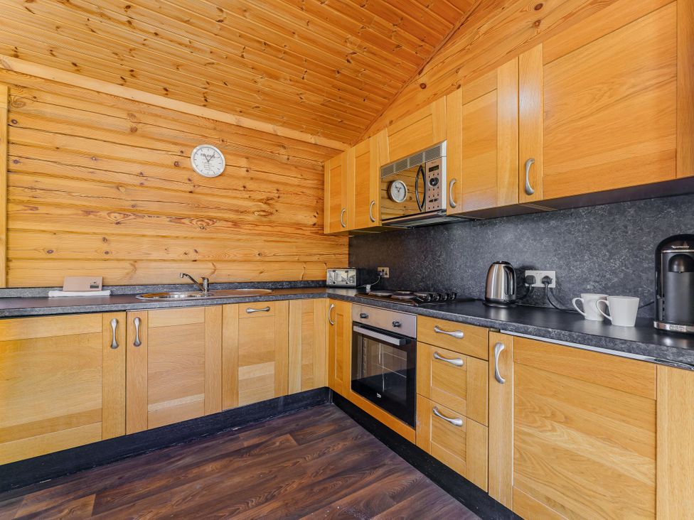 A kitchen with wooden cabinets and appliances at Yew Tree Spa (Pet) Carlton Miniott near Thirsk
