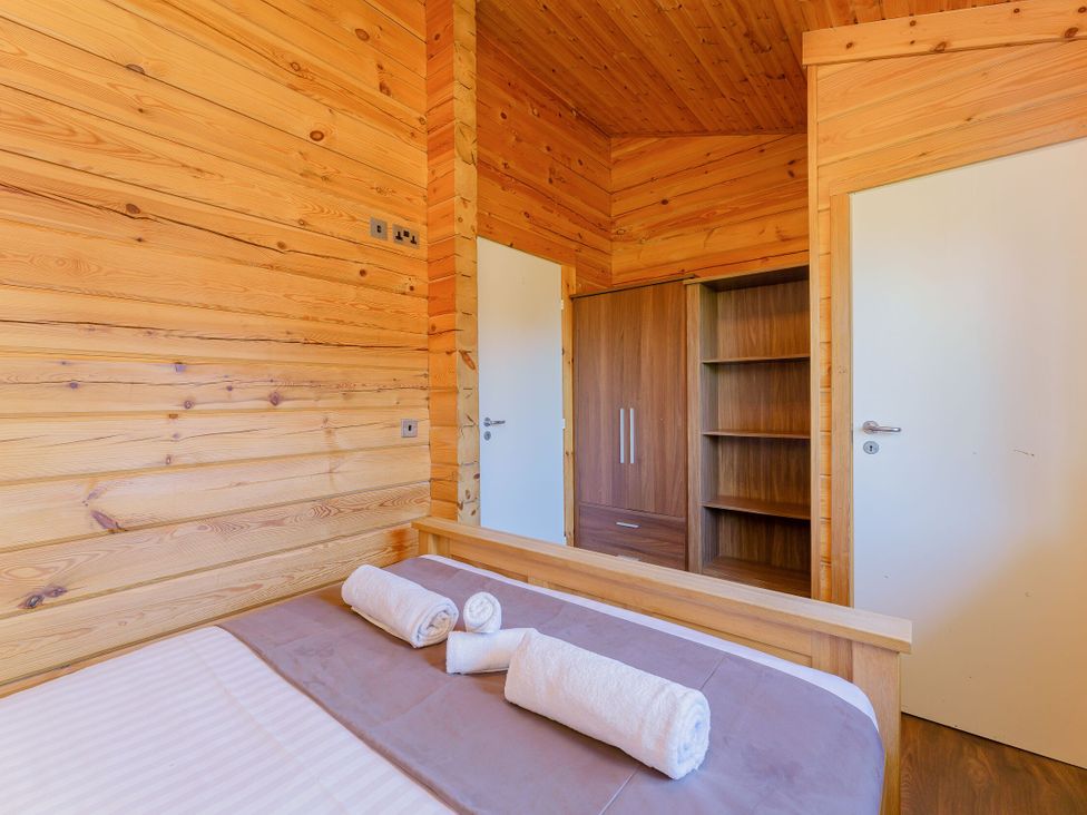 A bedroom with a bed and wardrobe at Yew Tree Spa (Pet) Carlton Miniott near Thirsk