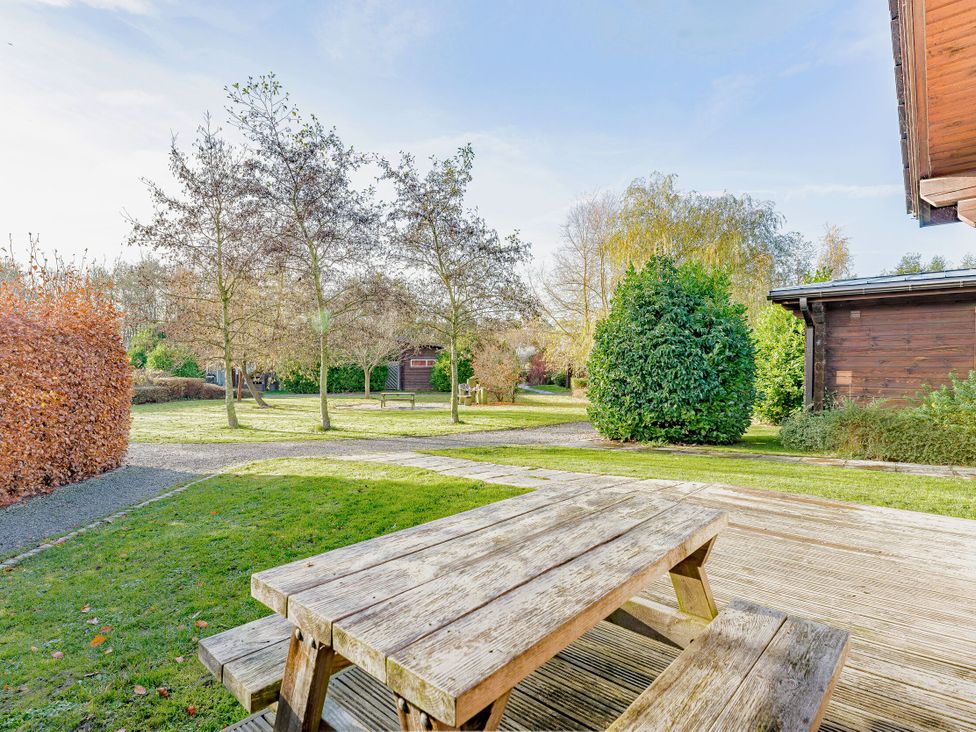 A garden with a wooden table and benches at Yew Tree Spa (Pet) Carlton Miniott near Thirsk