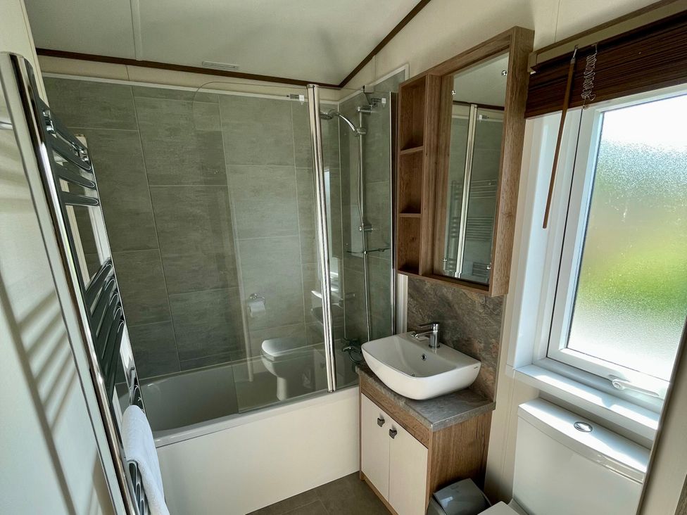 A bathroom featuring a shower, bathtub, sink, and toilet at Acacia Waterside Spa Carlton Miniott near Thirsk