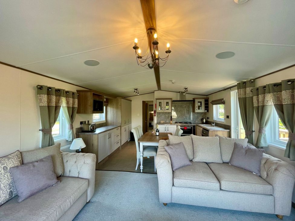 A living room with a sofa, dining table, and kitchen at Acacia Waterside Spa Carlton Miniott near Thirsk