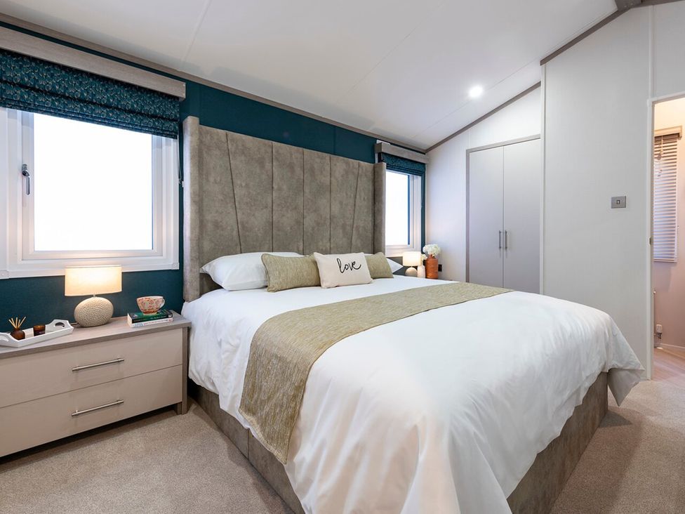 A bedroom with a bed and bedside table at Rowan Waterside Spa Carlton Miniott near Thirsk