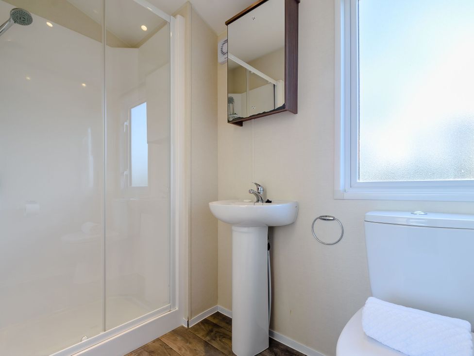 A bathroom with a shower, sink, toilet, and mirror at Alder Waterside Spa Carlton Miniott near Thirsk