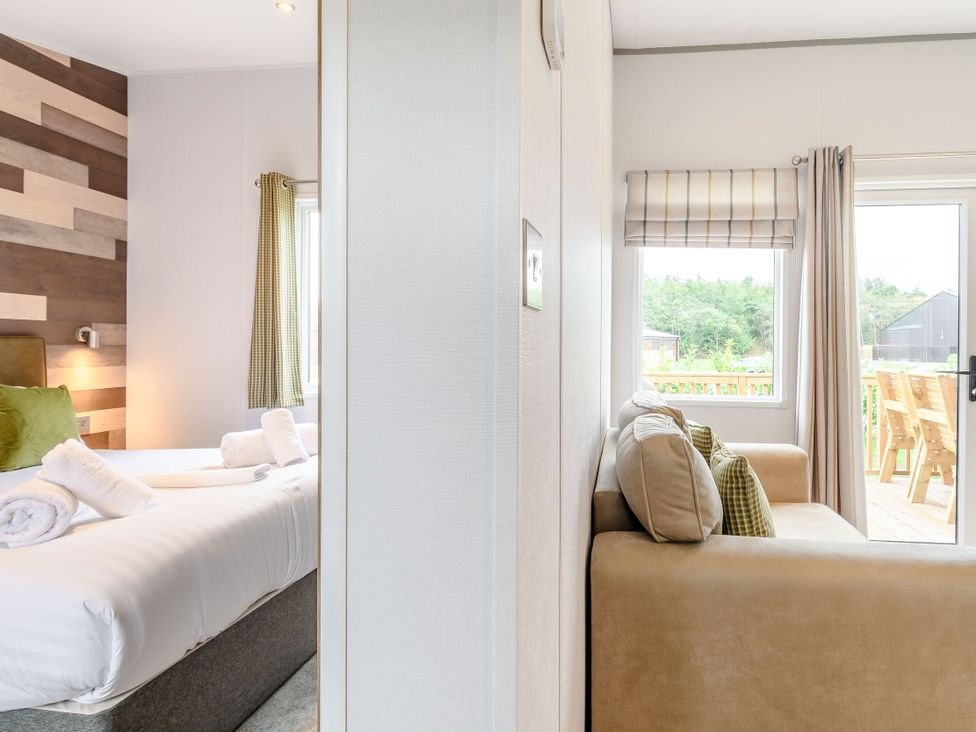 A bedroom with a bed and a living room with a sofa at Cedar in Carlton Miniott near Thirsk