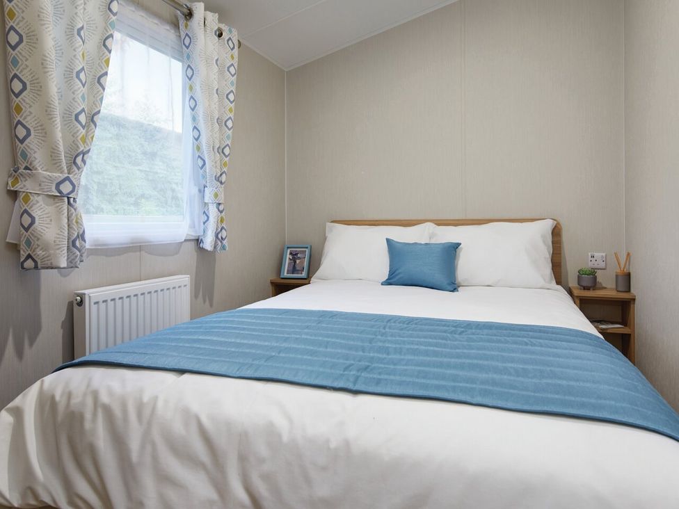 A bedroom with a bed and side table at Banyan Waterside Spa Carlton Miniott near Thirsk