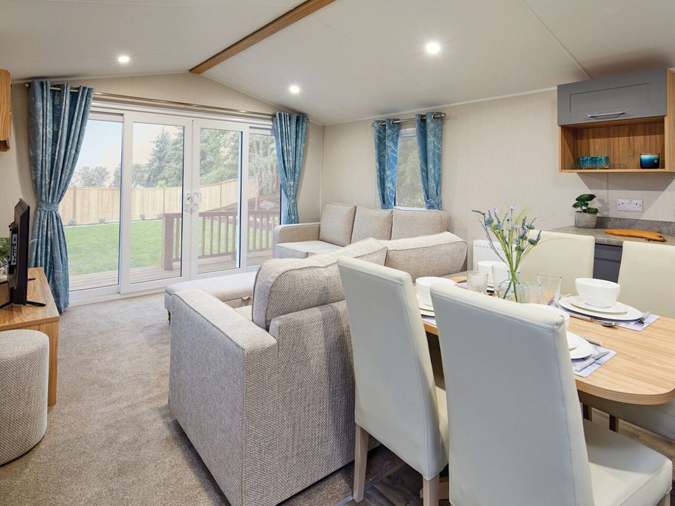 A living room with a dining area and exit to outdoor space at Banyan Waterside Spa in Carlton Miniott near Thirsk