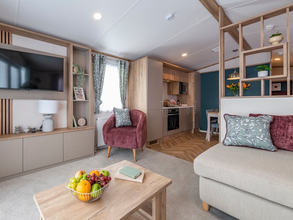 A living room with a television and kitchen area at Ellery Waterside Spa Carlton Miniott near Thirsk