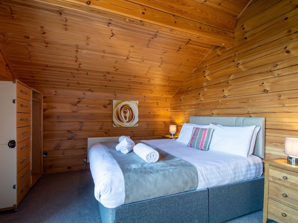 A bedroom with a bed and wooden walls at Birch Waterside Spa Carlton Miniott near Thirsk