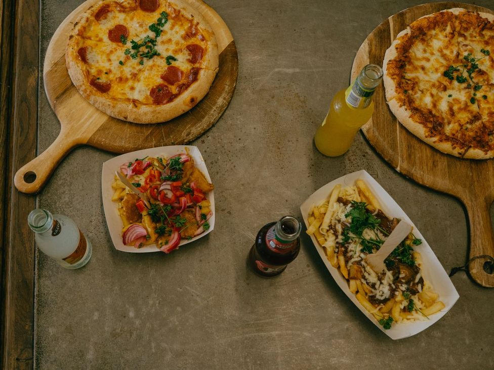 Two pizzas, french fries and drinks on a table