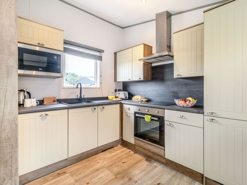 A kitchen with a sink, stove, and microwave at Cedar Spa in Carlton Miniott near Thirsk