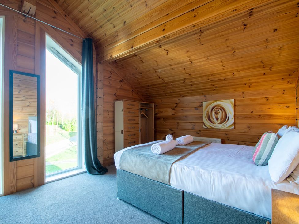 A bedroom with a bed and mirror at Birch Waterside Spa (Pet) in Carlton Miniott near Thirsk