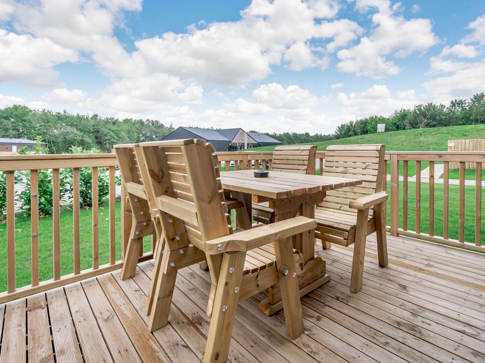 A table and chairs on a wooden deck at Cedar Spa (Pet) in Carlton Miniott near Thirsk