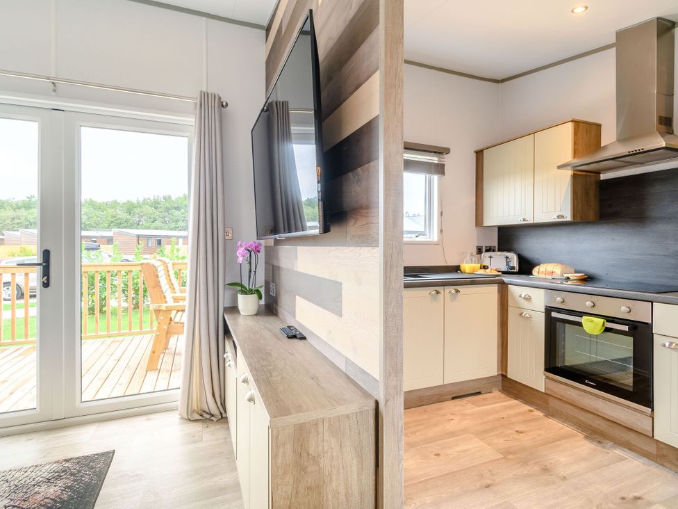 A kitchen with a television, cabinets, and a stove at Cedar Spa (Pet) Carlton Miniott near Thirsk